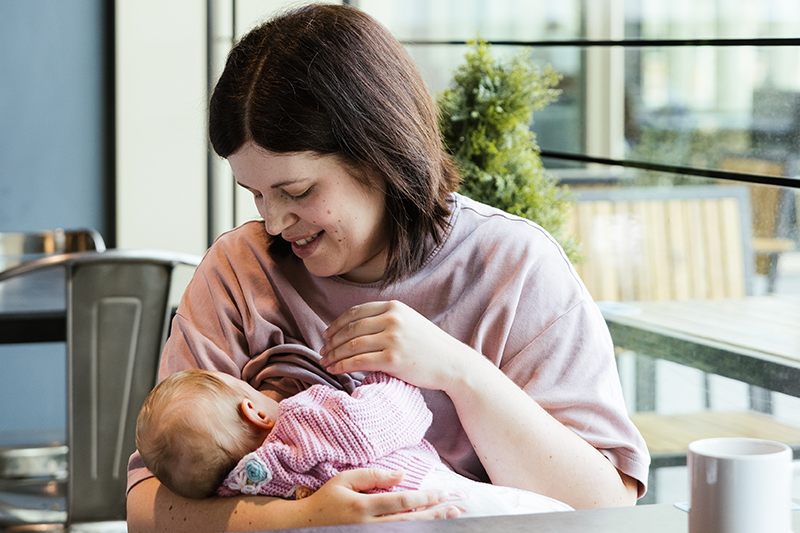A smiling mother breastfeeding in a cafe