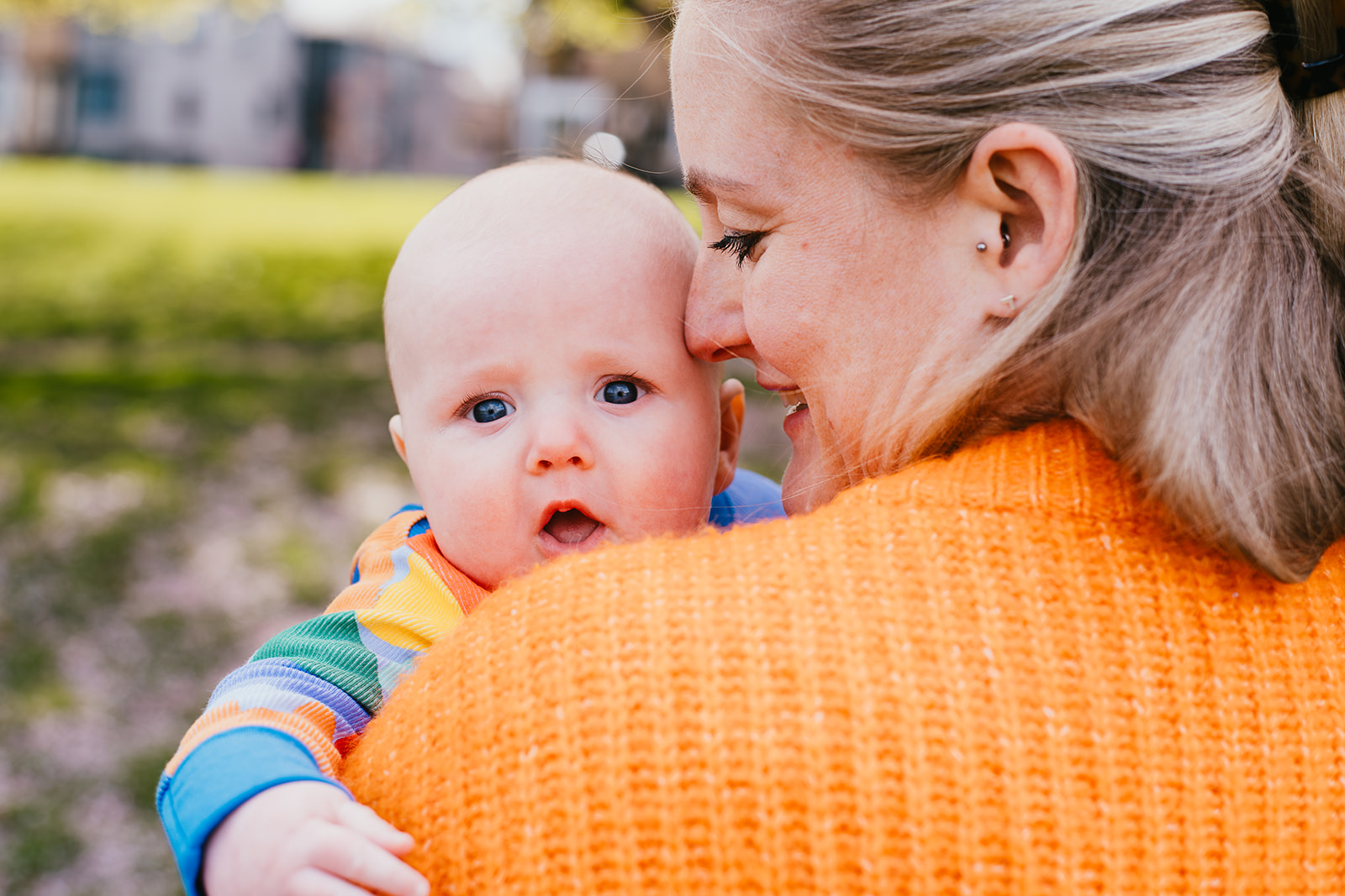 A woman holding a baby up to her shoulder. The baby is looking directly at the camera.