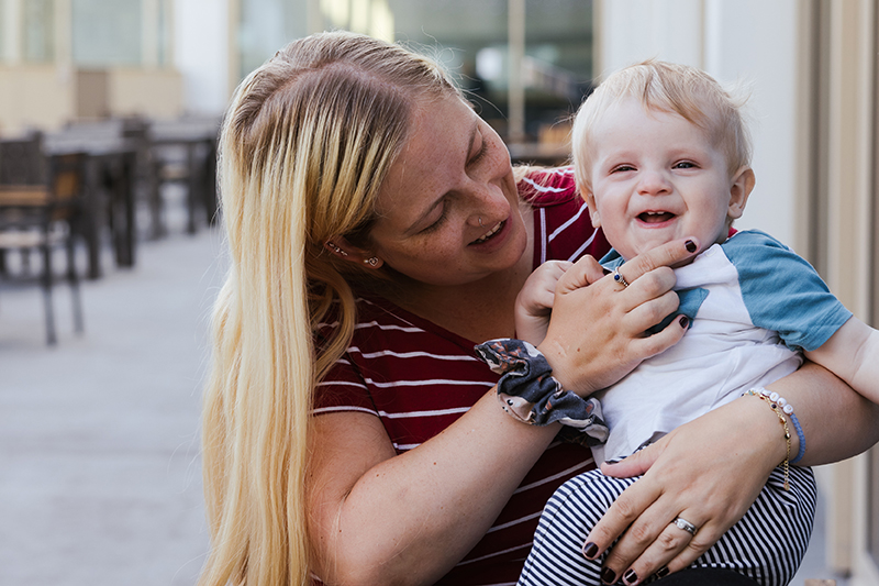 A woman holding an infant who is smiling at the camera