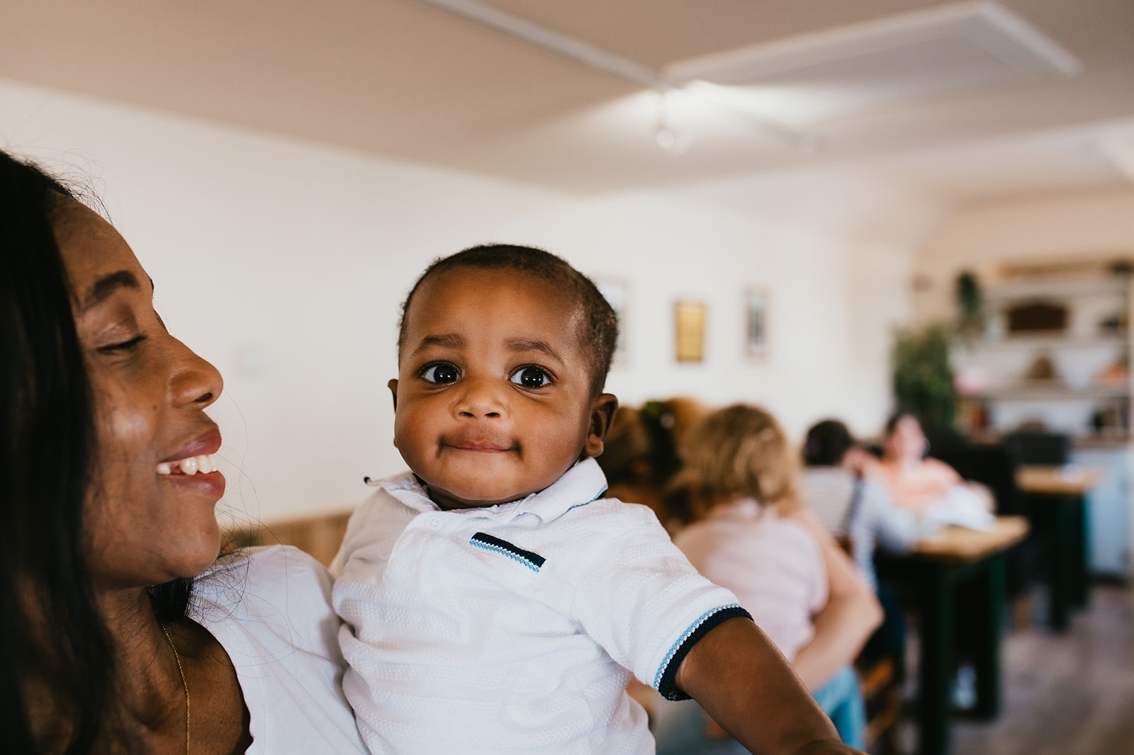 A woman holding a baby who is smiling at the camera
