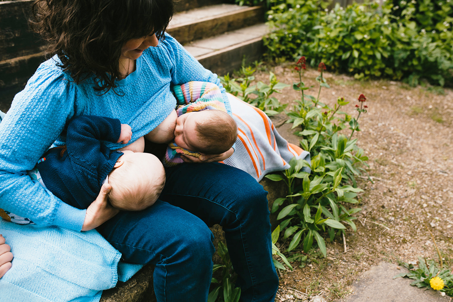 A mother holding two breastfeeding babies