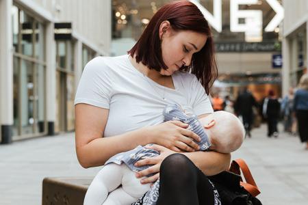 A woman breastfeeding a baby in a shopping centre