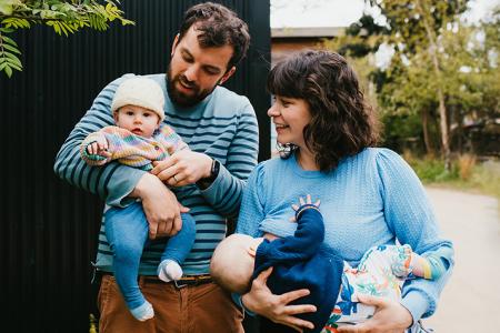 Mother breastfeeding and dad beside her holding a baby
