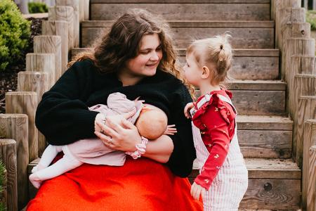Mother breastfeeding with a toddler beside her